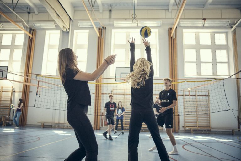 Elever spelar volleyboll i skolans idrottshall.