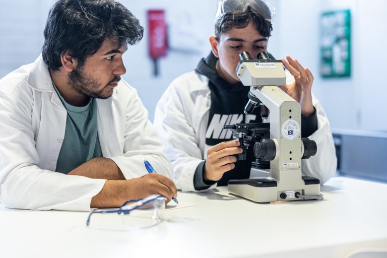 Två elever letar fram fakta i ett mikroskop.
