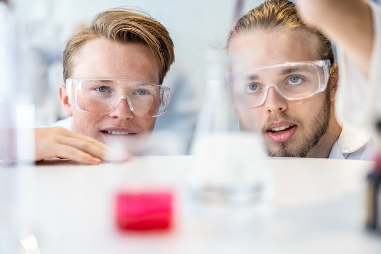 Två elever i närbild som laborerar i en labbsal.