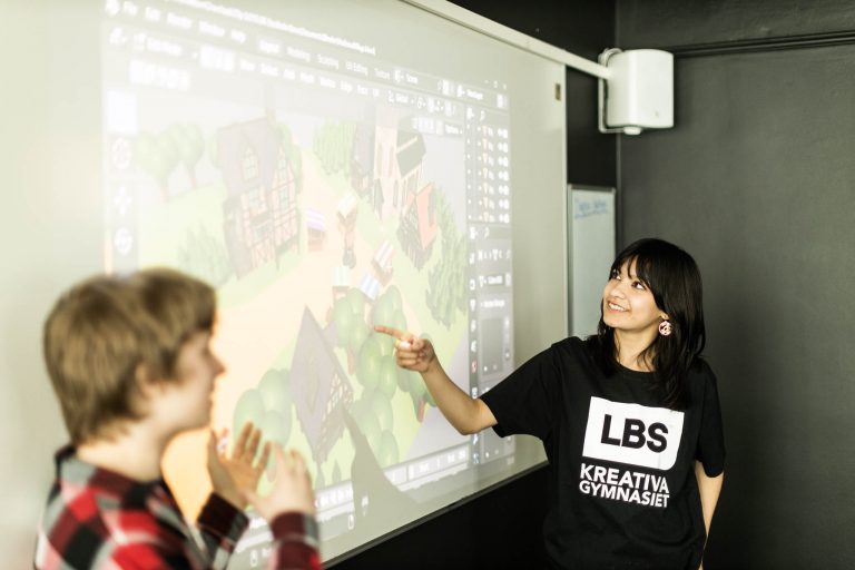 Två elever visar upp en spelmiljö på projektor