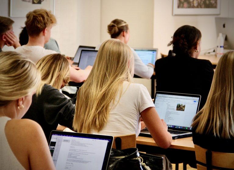 Elever i klassrummet, arbetar vid dator för att förbereda en presentation.
