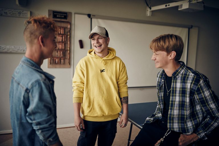 Tre glada elever skrattar när de umgås i skolans matsal