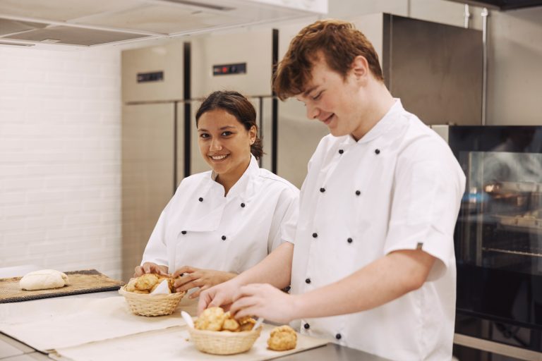 Två elever lägger upp bröd i metodköket där undervisningen sker på restaurangprogrammet