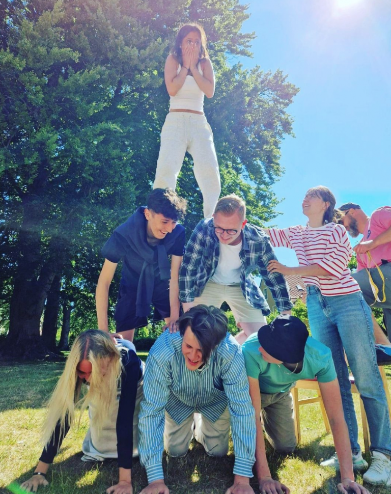 Elever gör en gruppövning att skapa en pyramid i parken utanför Quennerstedska villan en solig dag.