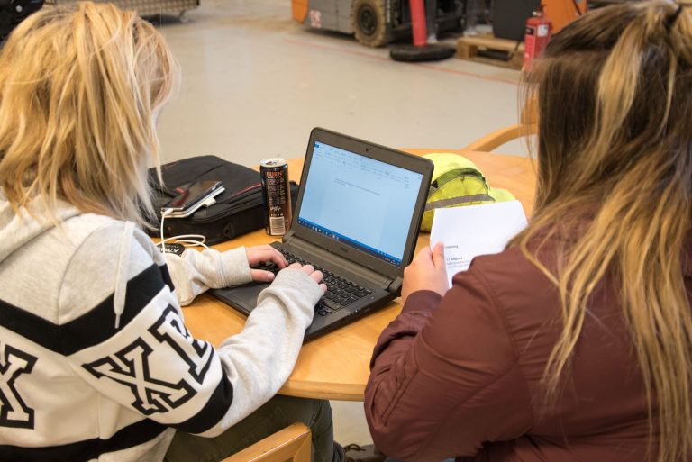 Bild på två tjejer som sitter framför en dator och jobbar med teori på transportprogrammet